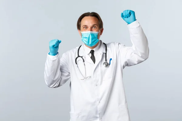 Covid-19: 바이러스 예방, 의료 종사자 및 예방 개념. 의사가 의료용 마스크와 장갑을 착용하고 손을 들어 환호성을 지르며 목표 달성을 축하 함 — 스톡 사진