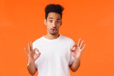 Eleman değerlendirmesi kötü film hakkında bilgi veriyor. Beyaz tişörtlü sevimli hippi, modern Afro-Amerikan erkek kişisel görüşlerini ifade ediyor, iyi bir jest, turuncu arka planda duruyor.