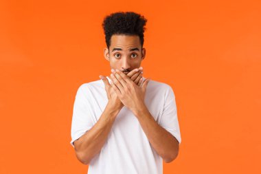 Tanrım, ben ne yaptım? Utanmış ya da garip genç şokta, nutku tutulmuş Afro-Amerikan erkek ağzı kapalı ve utangaç görün, dil sürçmesi, gizli birine anlatmış, turuncu arka plan