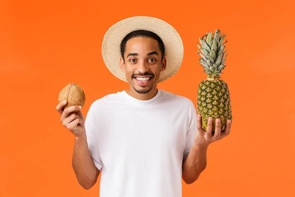 여행, 휴식, 레저 개념. 신나게 행복 한 젊은 아프리카 계 미국인 남자 친구가 예약 한 호텔 과 해외로 여행하는 티켓은 코코넛 과 파인애플을 들고 햇살 과 맛있는 과일을 즐긴다 — 스톡 사진