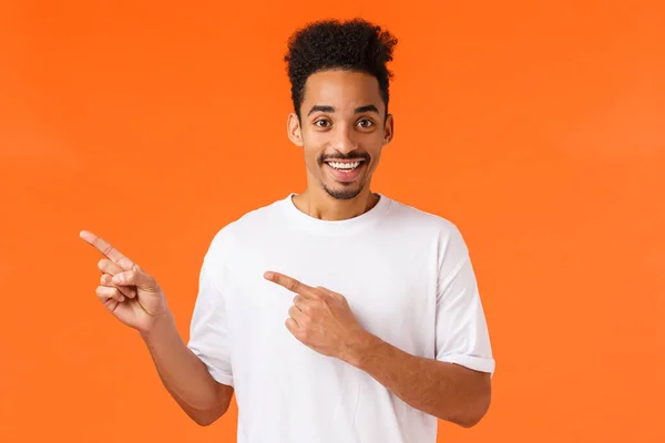 Animado e divertido feliz sorrindo, homem afro-americano com corte de cabelo afro, sorrindo desfrutando de evento incrível ou perfomance, visite um lugar legal e sugira ir juntos, apontando canto superior esquerdo — Fotografia de Stock