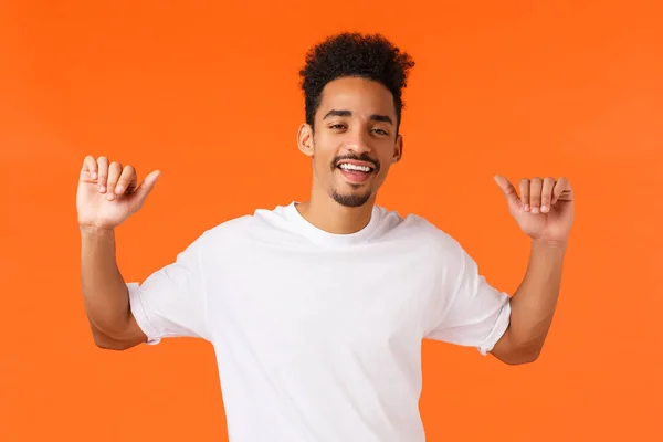 Cool and stylish, boastful african-american male with tattoos, moustache, pointing thumbs at himself and smirk cheeky, feeling assertive and self-assured, proud own achievement, orange background — Stock Photo, Image