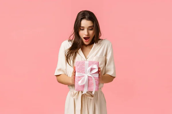 El asombro, la celebración y el concepto de vacaciones. Sorprendida novia celebración caja de regalo, no expact recibir regalo, boca abierta fascinado mirada tocada caja envuelta, fondo rosa —  Fotos de Stock