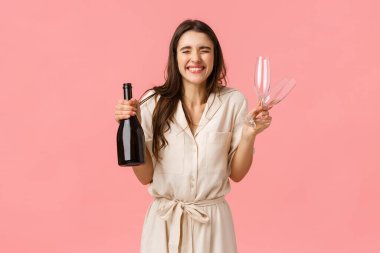 Happiness, celebration and congratulations concept. Charming and excited, ecstatic caucasian woman in dress, close eyes and smiling joyfully, eager open bottle champagne and drink together