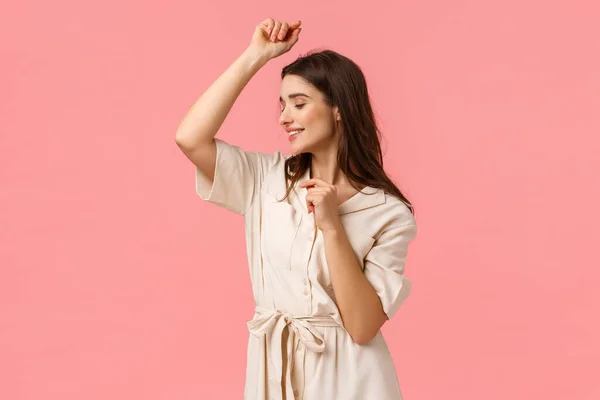 Romantic and sensual beautiful young woman in dress, partying raising hands up and smiling cute, dancing enjoying leisure, having fun on weekend trip, standing pink background — 스톡 사진