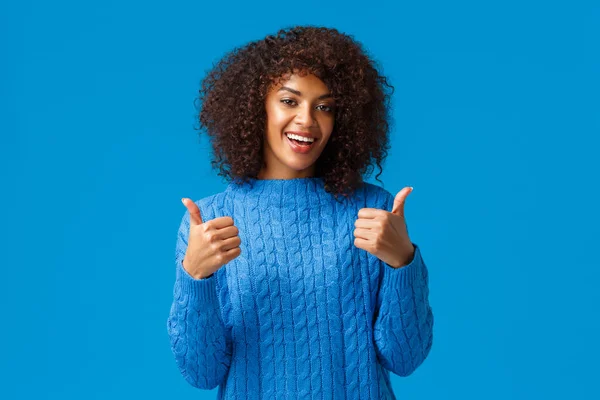 Todo súper genial. Mujer afroamericana alegre y satisfecha con corte de pelo afro, sonriendo y mostrando pulgares hacia arriba en aprobación, como producto, recomienda software o aplicación, de pie fondo azul — Foto de Stock