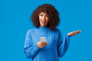 Neler oluyor, biri bana açıklasın. Kafası karışmış ve hayal kırıklığına uğramış, kışın kazak giyen Afro-Amerikan kadını rahatsız eden, omuz silken, korku içinde el kaldıran, sorgulanmış ve kızgın görünen, akıllı telefon tutan