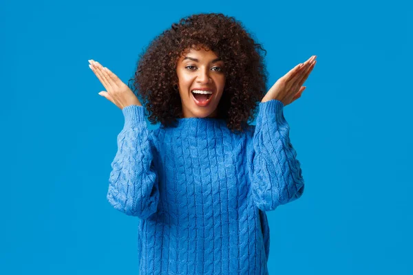 可爱又顽皮，有趣的快乐的非洲裔美国女人，穿着冬季毛衣，睁大眼睛看节日惊喜，情人节礼物，凝视着欢乐的蓝色背景 — 图库照片