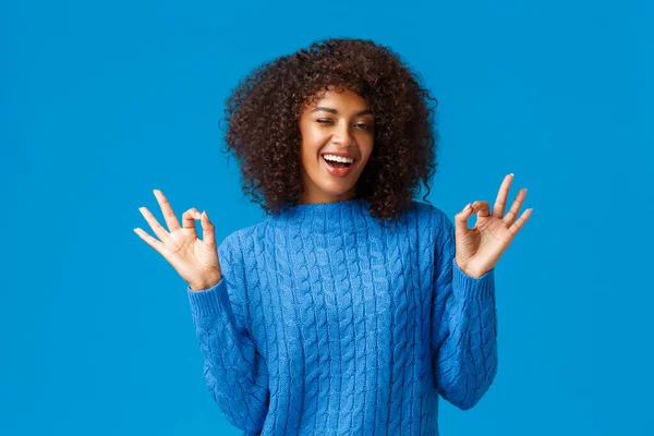 Nyugi és nyugi, minden rendben. Vidám, jóképű, gondtalan, fiatal afro-amerikai nő, aki nyugodt, oké gesztus, minden szép és mosolygós, álló kék háttér elégedett — Stock Fotó