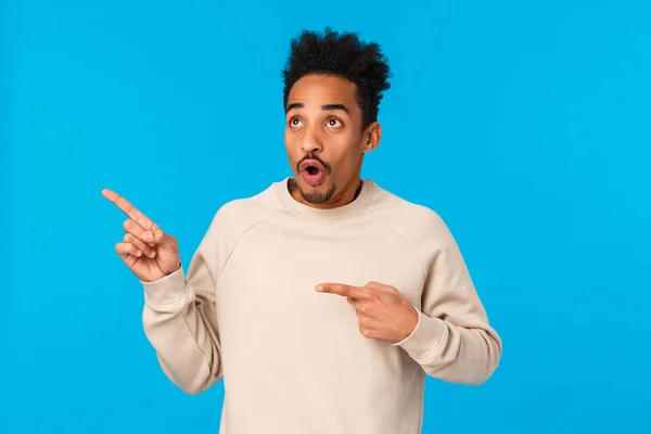 Speechless and impressed, startled attractive african-american boyfriend seeing just what he need, losing speech standing blue background, open mouth staring upper left corner amazed — Stock Photo, Image