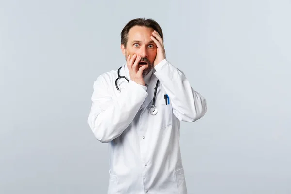 Covid-19, ξέσπασμα του ιού της στέψης, επαγγελματίες υγείας και πανδημία. Σοκαρισμένος και ανήσυχος άντρας γιατρός με λευκό παλτό, λαχανιασμένος, να δείχνει φοβισμένος από πανικό στην κάμερα — Φωτογραφία Αρχείου