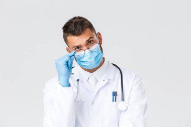 Covid-19, sağlık çalışanları, salgın hastalıklar ve virüs önleme konsepti. Beyaz önlüklü, steteskoplu, tıbbi maskeli, ilgili bakan doktorlara yakın çekim.