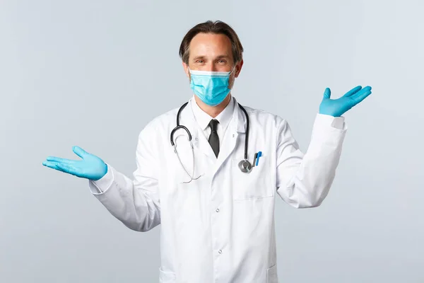 Covid-19, πρόληψη του ιού, εργαζόμενοι στον τομέα της υγείας και την έννοια του εμβολιασμού. Χαμογελώντας όμορφος γιατρός δίνουν δύο παραλλαγές, φορούν ιατρική μάσκα και γάντια, δείχνοντας αριστερά και δεξιά προϊόντα, λευκό φόντο — Φωτογραφία Αρχείου