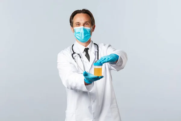 Covid-19: 바이러스 예방, 의료 종사자 및 예방 개념. 의료용 마스크와 장갑을 낀 유쾌 한 웃는 의사는 깨끗 한 검사 결과와 하얀 배경으로 만족 한 소변 샘플을 보여준다 — 스톡 사진