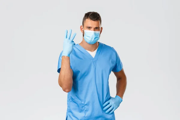 Εργάτες υγείας, Covid-19, Coronavirus και έννοια του ιού. Όμορφος γιατρός, νοσοκόμος με ποδιά και μάσκα. Δείχνει το νούμερο τρία, καταπολεμά τη μόλυνση κατά τη διάρκεια πανδημίας. — Φωτογραφία Αρχείου