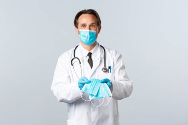 Covid-19, virüsü önleme, sağlık çalışanları ve aşı konsepti. PPE 'deki faydalı erkek doktor hasta Coronavirus hastalarına tıbbi maske veriyor.