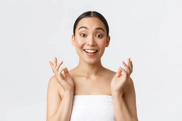 Beauty, cosmetology and spa salon concept. Surprised and happy beautiful asian girl in towel react to clean perfect skin after skincare or massage therapy, look impressed and satisfied — Stock Photo, Image
