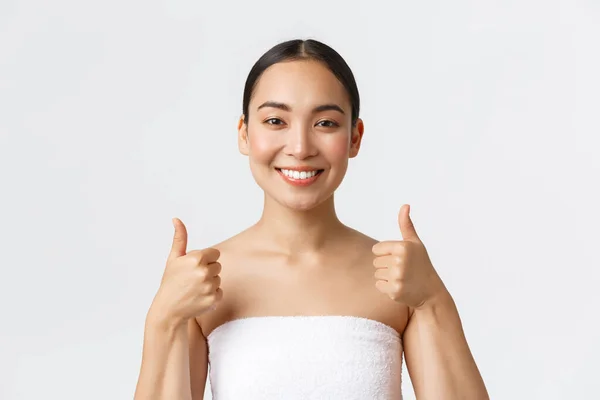 Kecantikan, kosmetologi dan konsep salon spa. Wanita Asia yang cukup puas dengan handuk putih meninggalkan ulasan positif setelah terapi pijat atau prosedur kosmetik perawatan kulit, menunjukkan jempol seperti dan persetujuan — Stok Foto