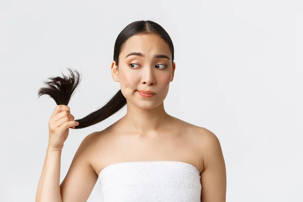 Kecantikan, produk rambut rontok, sampo dan konsep perawatan rambut. Wanita asia cantik bermasalah dengan handuk mandi melihat ujung-ujungnya, membutuhkan perawatan rambut, latar belakang putih berdiri — Stok Foto