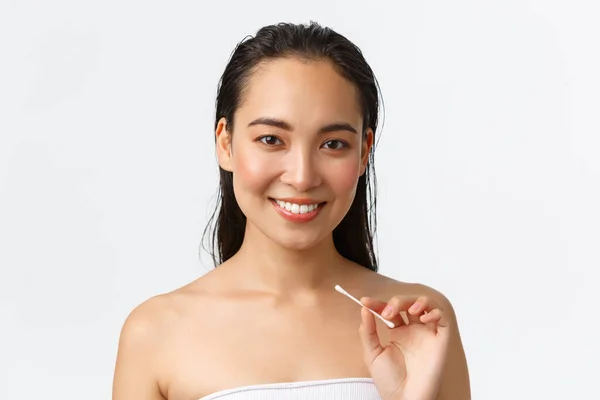 Skincare, women beauty, hygiene and personal care concept. Close-up of beautiful asian girl standing naked in bathroom or shower, holding cotton buds, swabs for ears, standing white background — Stock Photo, Image