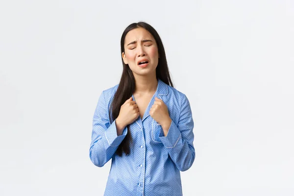 Miserable y triste chica asiática en pijama azul llorando y quejándose, sintiéndose angustiado, de pie molesto sobre fondo blanco, pidiendo ayuda o duelo, posando sobre fondo blanco —  Fotos de Stock