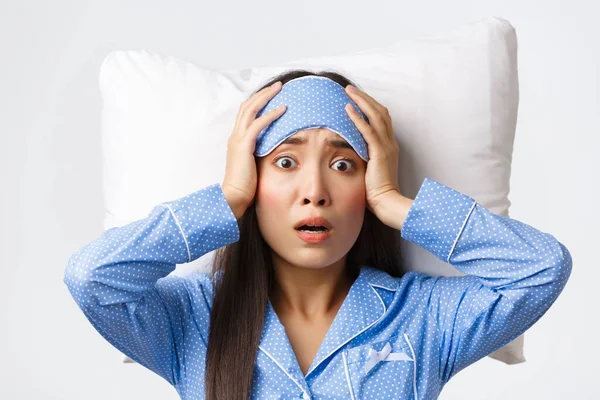 Primer plano de pánico asiático linda chica acostada en la cama en la almohada en la máscara de dormir y pijamas, buscando ansioso y preocupado, darse cuenta de que algo malo sucedió, pose fondo blanco preocupado —  Fotos de Stock