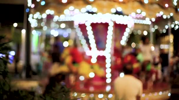 Blur kind spelen op carrousel en bokeh van licht 's nachts. — Stockvideo