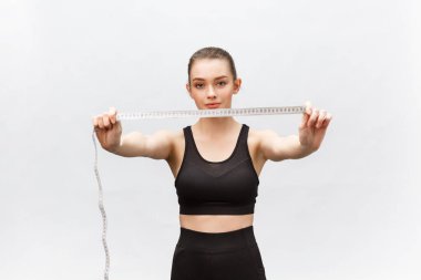 Beyaz arka planda izole edilmiş mezura ile gülümseyen çekici beyaz kadın portresi.