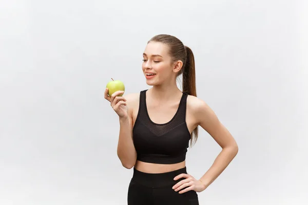 Retrato de uma jovem mulher caucasiana feliz segurando e comendo maçã verde sobre fundo branco — Fotografia de Stock