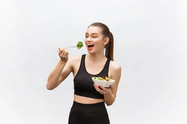 Joven hermosa mujer del deporte comiendo ensalada sobre fondo blanco . —  Fotos de Stock