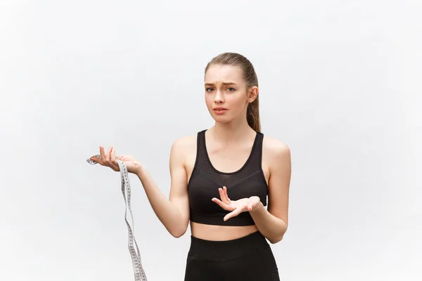 Portrait of an upset sad woman holding measuring tape looking at camera isolated over white background — Stock Photo, Image