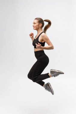 Gri arka planda mutlu, güzel bir fitness kadınının tam boy resmi.