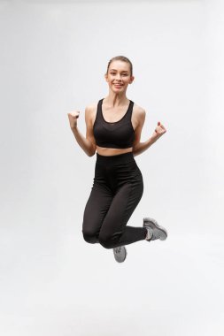 Gri arka planda mutlu, güzel bir fitness kadınının tam boy resmi.