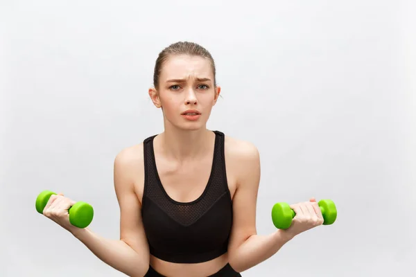 Sad Caucasian young woman with long medium brown hair in casual outfit holding dumbbell - Isolated — Stock Photo, Image