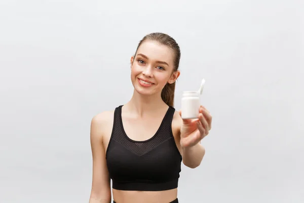 Sorrindo loira esporte mulher segurando garrafa de remédio no fundo branco — Fotografia de Stock