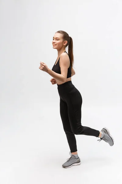 Imagen completa de una mujer deportiva corriendo en el estudio sobre fondo gris . — Foto de Stock