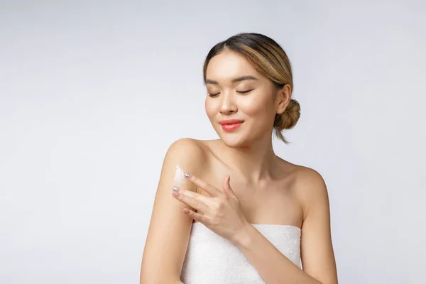 Wanita Asia mengoleskan krim kosmetik pada kulit pada latar belakang putih yang terisolasi — Stok Foto