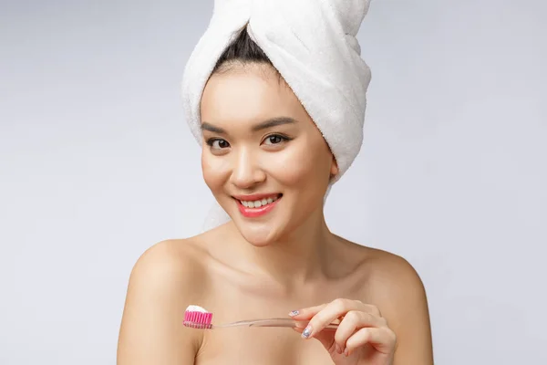 Gyönyörű fiatal nő fehér elszigetelt háttér tart egy fogkefe, ázsiai — Stock Fotó