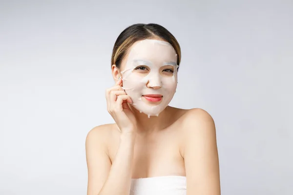 Spa, healthcare. Asian girl with a cosmetic mask isolate on white. — Stock Photo, Image