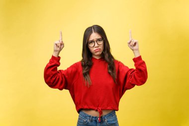 Genç, güzel Asyalı bir kadın, sarı arka planda izole edilmiş, boşluğu işaret ediyor.