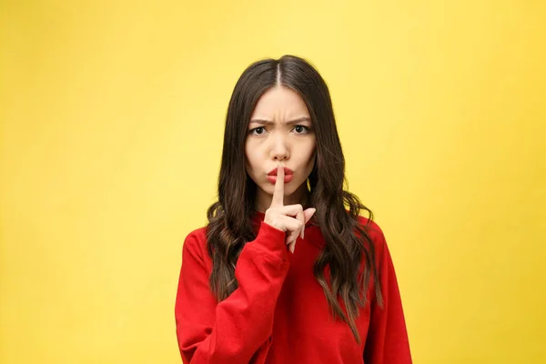 Mujer joven sobre la pared amarilla mostrando un gesto de silencio poniendo el dedo en la boca — Foto de Stock