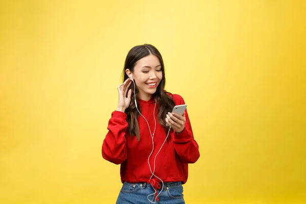 Portret szczęśliwej kobiety słuchającej muzyki w słuchawkach i tańczącej na żółtym tle — Zdjęcie stockowe