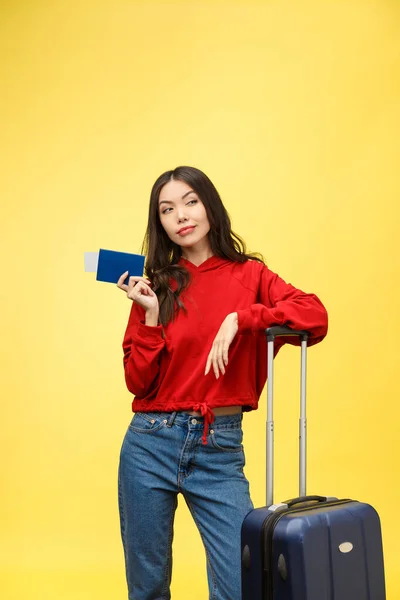 Frauen reisen. Junge schöne asiatische Reisende mit Koffer und Pass auf gelbem Hintergrund — Stockfoto