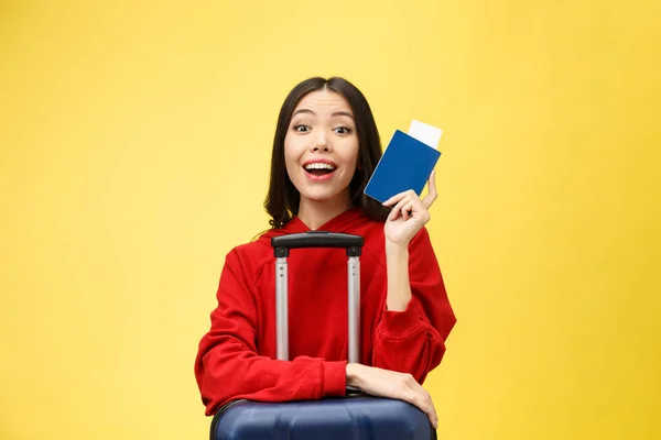 Le donne viaggiano. Giovane bella donna asiatica viaggiatore con passaporto e valigia su sfondo giallo — Foto Stock