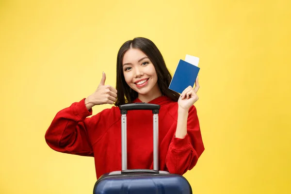 Le donne viaggiano. Giovane bella donna asiatica viaggiatore con passaporto e valigia su sfondo giallo — Foto Stock