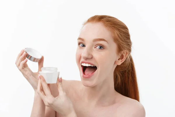 Retrato de mulher bonita sorrindo enquanto toma algum creme facial isolado no fundo branco com espaço de cópia . — Fotografia de Stock