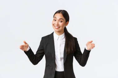 Gülümseyen Asyalı satış elemanı müşteriye ürün satıyor, büyük nesneleri şekillendiriyor ve kameraya dostça sırıtıyor. İş kadını projesini halka tanıtıyor, geniş bir daire ve beyaz arka plan tanıtıyor.