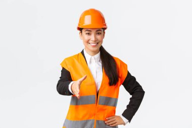 Başarılı bir kadın mimar, güvenlik kaskı, yansıtıcı ceket, el sıkışmak için soyu tükenmiş ve el sıkışma, inşaat alanında iş ortaklarını karşılama, beyaz arka plan