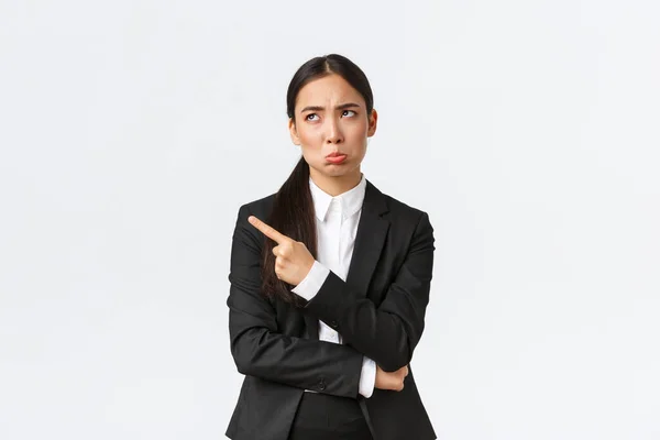 Upset and disappointed female entrepreneur, broker in suit grimacing, pouting displeased and sad as looking and pointing upper left corner uneasy, standing white background — Stock Photo, Image