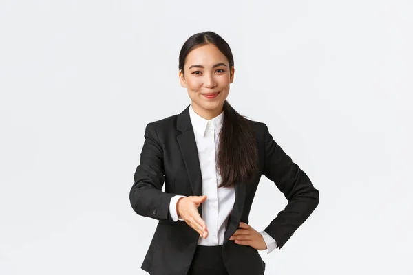 Femme d'affaires avec succès confiante en costume noir étendre la main pour poignée de main, saluant partenaire d'affaires avec sourire heureux déterminé, contrat prêt à signer, fond blanc — Photo